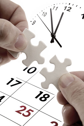 Manos con dos piezas de puzle que encajan delante de un reloj y un calendario.
